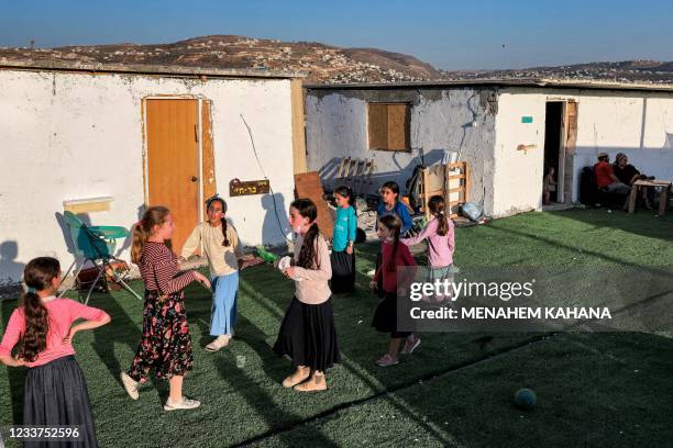 Girls gather on artificial turf laid out outside Israeli settlers' shacks in the newly-established wildcat outpost of Eviatar near the northern...