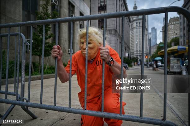 An impersonator wearing a mask resembling former US president Donald Trump poses for photos outside the Criminal Courts building and District...