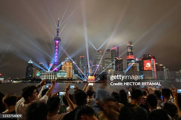 Spectators look at a light show on the Bund promenade in Shanghai on July 1 as the country marks the 100th anniversary of the founding of China's...