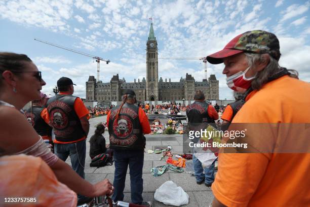 Demonstrators wearing orange in solidarity with survivors of residential schools gather at a memorial in front of Parliament Hill on Canada Day in...