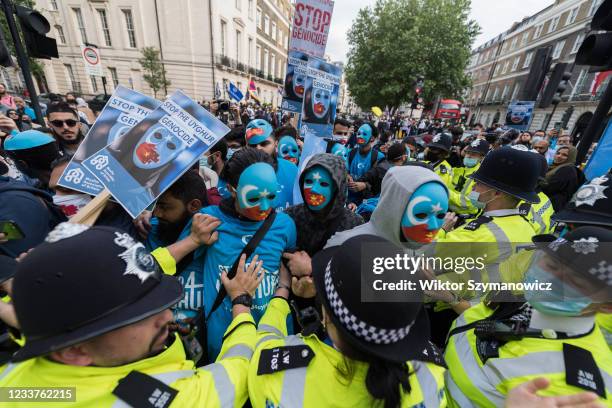 Police officers scuffle with protesters who were trying to block the road during a demonstration in front of the Chinese Embassy in support of the...