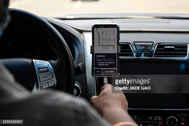 Driver uses the Didi Chuxing ride-hailing app on his smartphone while driving along the street in Beijing on July 2, 2021.