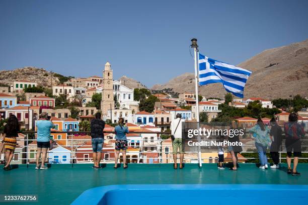 Tourists on a ferry take pictures during the arrival to the island of Halki, Greece on July 1, 2021.