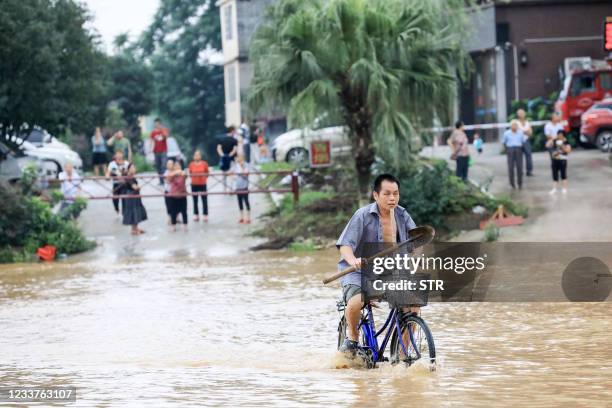 Man rides a bicycle on a flooded street along the swollen Rongjiang river after heavy rains in Rongan, in China's southern Guangxi region on July 2,...