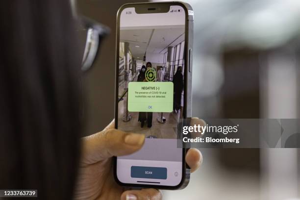Smartphone enabled with Covid-19 detection software, developed by EDE Research Institute, shows a negative scan for a visitor at entrance of Yas...