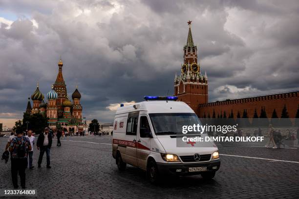 Picture taken on July 1, 2021 shows an ambulance driving across Red Square with the St. Basil's Cathedral and Kremlin's Spasskaya Tower in the...