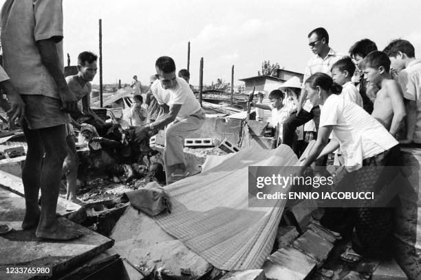 Vietnamese people evacuate a dead body among the rubble of destroyed houses following an attack by Vietcong army in Ben Cat on April 27, 1972 during...