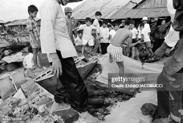 Vietnamese people evacuate a dead body among the rubble of destroyed houses following an attack by Vietcong army in Ben Cat on April 27, 1972 during...