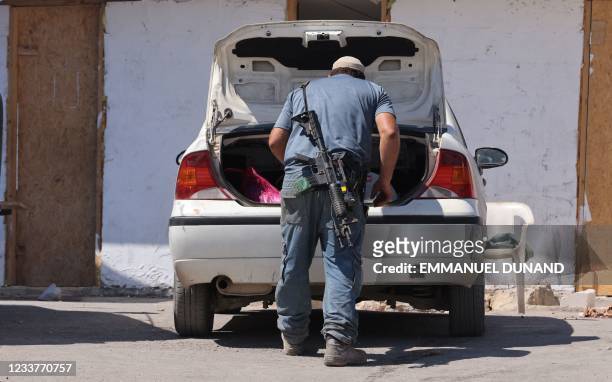 An armed Israeli settler gathers belongings in his car before evacuating the newly-established wildcat outpost of Eviatar in Beita, near the northern...