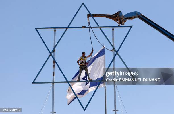 An Israeli settler adds the finishing touches to a large Star of David before evacuating the newly-established wildcat outpost of Eviatar in Beita,...