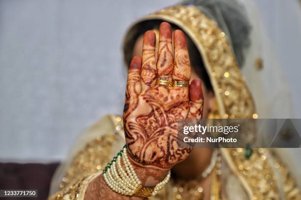 Bride hides her face with her Henna Painted hand during her wedding in Baramulla, Jammu and Kashmir, India on 02 July 2021.