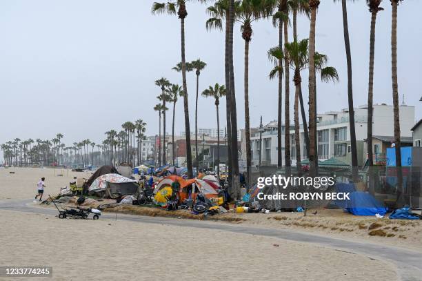 Man jogs along the beach as authorities prepare to begin clearing homeless encampments at the Venice Beach Boardwalk ahead of the Independence Day...