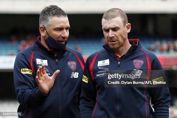 Midfield coach Adem Yze and senior coach Simon Goodwin of the Demons speak during the 2021 AFL Round 16 match between the Melbourne Demons and the...