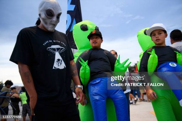 People in costume visiting from El Paso, Texas walk together following the Abduction parade during the UFO Festival on July 2, 2021 in Roswell, New...