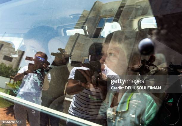 Reporters take images of Russian orphans born to parents linked to the Islamic State as they wait in a bus before Syrian Kurdish authorities hand...