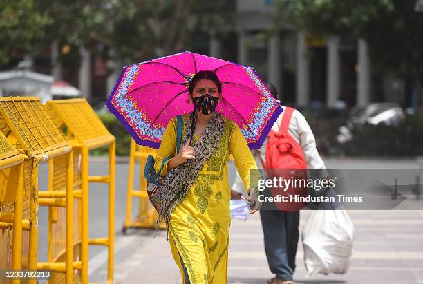 Woman walks under an umbrella on a hot summer day, on July 2, 2021 in New Delhi, India.