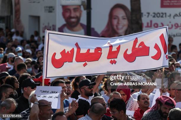 Palestinians lift placards in Arabic which read "What a situation: Occupation... Deceit... Arrest... Assassination" as a banner addressing...