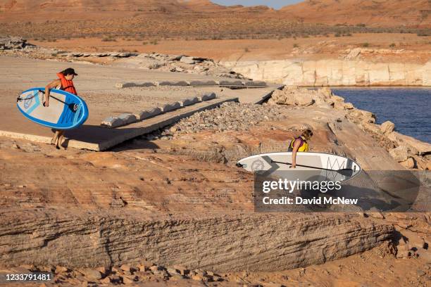 Paddle boarders climb down the drop-off below the Antelope Point boat launch ramp which was made unusable by record low water levels at Lake Powell...