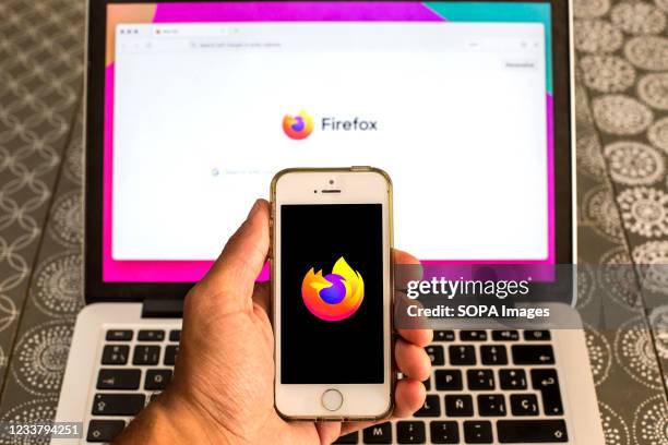 In this photo illustration, a Mozilla Firefox web browser logo seen displayed on a smartphone in front of a laptop.