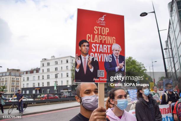 Protester holds a 'Stop Clapping, Start Paying' placard during the NHS workers demonstration outside University College Hospital. NHS workers and...