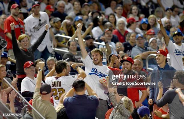 Dodgers fan celebrates after catching a foul ball in the stands behind home plate during the Los Angeles Dodgers versus Washington Nationals MLB game...