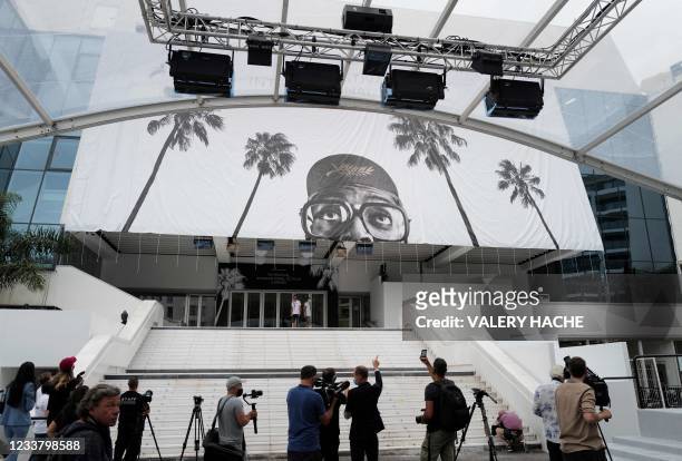 Journalists take images as workers install a giant banner at the Palais des Festivals et des Congres in Cannes, southeastern France, on July 4 two...