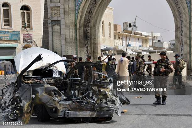 Afghan security forces personnel inspect the remains of a vehicle at the site of a bomb blast in Kandahar on July 4, 2021.