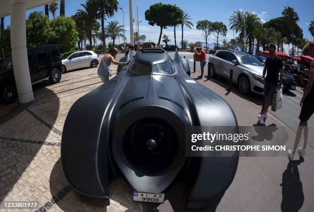 Passers-by take pictures of a Batmobile, parked in front of the Martinez palace in Cannes, Southeastern France, on July 4 two days before the start...