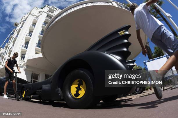 Passers-by look at a Batmobile, parked in front of the Martinez palace in Cannes, Southeastern France, on July 4 two days before the start of the...