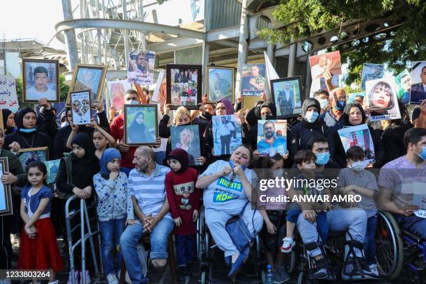 Relatives of victims of Beirut's port blast hold their pictures as they rally in the Lebanese capital on July 4 to urge answers from a sluggish probe...