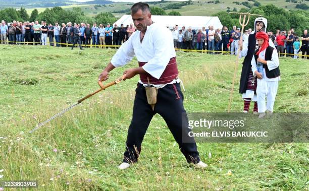 Bosnian man swings his scythes during the traditional grass mowing competition on July 4, 2021 in the village of Strljanica, near the western-Bosnian...