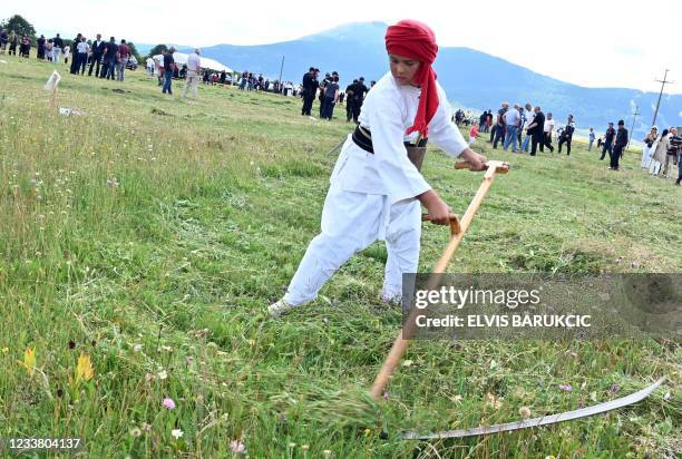 Bosnian boy swings his scythe during the traditional grass mowing competition on July 4, 2021 in the village of Strljanica, near the western-Bosnian...