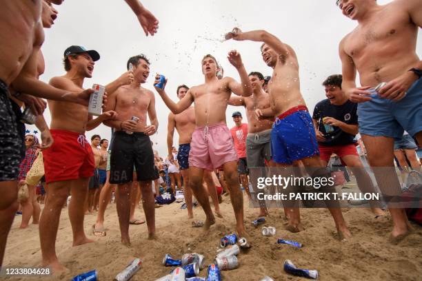 Participants chug beer on the beach during the 47th annual Hermosa Beach Ironman competition where participants must run a mile, paddle a surfboard a...