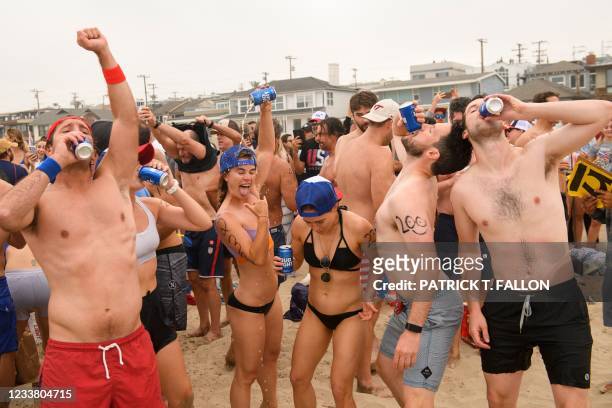 Participants chug beer on the beach during the 47th annual Hermosa Beach Ironman competition where participants must run a mile, paddle a surfboard a...