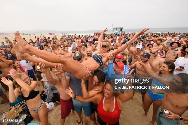 Repeat female champion Annie Seawright-Newton is lifted into the air after winning the 47th annual Hermosa Beach Ironman competition where...