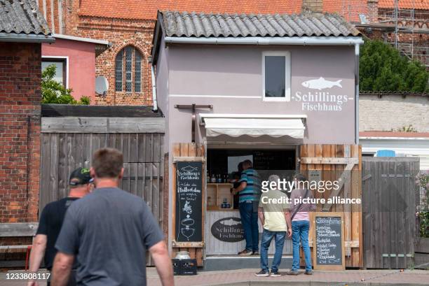June 2021, Mecklenburg-Western Pomerania, Schaprode: Before boarding the ferry to Hiddensee, tourists like to buy a fish sandwich in the harbour of...