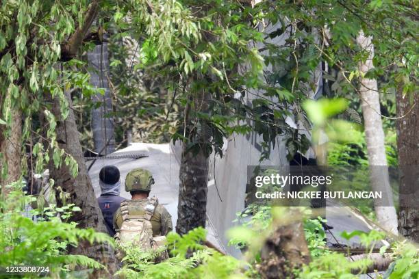 Philippine soldiers stand near wreckage of a Philippine Air Force C-130 transport aircraft, which crashed July 4 and killed 50 people after it...