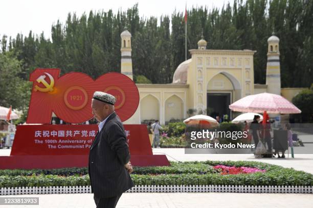 Photo taken July 3, 2021 shows a man walking near a monument commemorating the 100th anniversary of the founding of the Chinese Communist Party in...