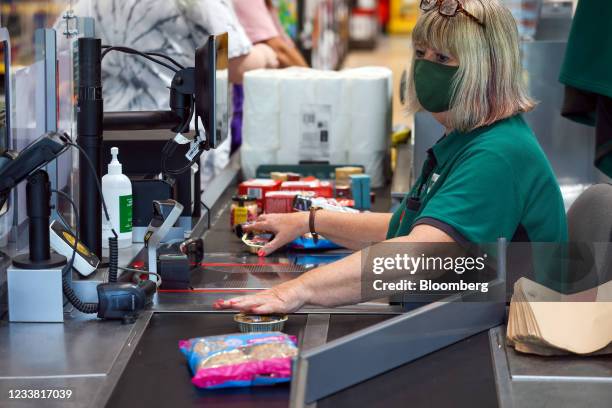 An employee passes goods along a conveyor belt at a checkout in a Morrisons supermarket, operated by Wm Morrison Supermarkets Plc, in Saint Ives,...