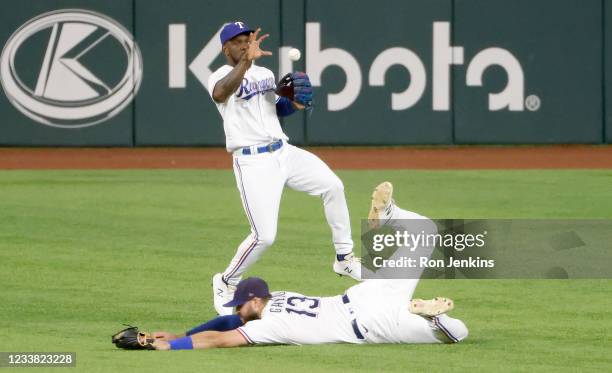 Joey Gallo of the Texas Rangers dives as teammate Adolis Garcia fields a single off the bat of Nomar Mazara of the Detroit Tigers during the eighth...