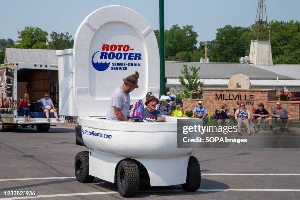 Two men drive a toilet-shaped vehicle sponsored by Roto-Rooter during the Independence Day parade. Local organizations, businesses and former...