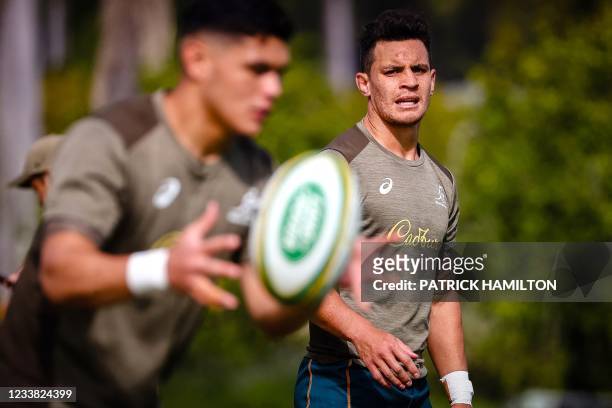 Australia's rugby player Noah Lolesio catches the ball as a teammate Matt To'omua looks on during a captain's run at Sanctuary Cove in Gold Coast on...