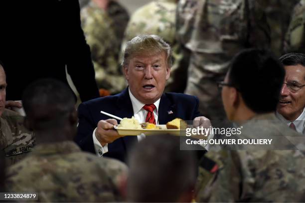 In this file photo taken on November 28, 2019 former US President Donald Trump serves Thanksgiving dinner to US troops at Bagram Air Field during a...