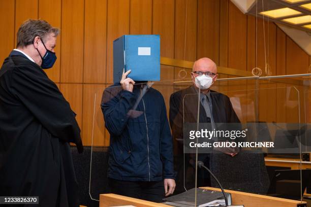 The main defendant standing between his lawyers Udo Vetter and Wilfried Rath hides his face behind a folder as he arrives for his judgement in a...