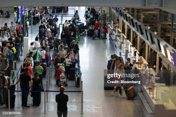 Travelers queue for flights at the TUI AG flight check-in desks at Frankfurt Airport in Frankfurt, Germany, on Tuesday, July 6, 2021. TUI has raised...