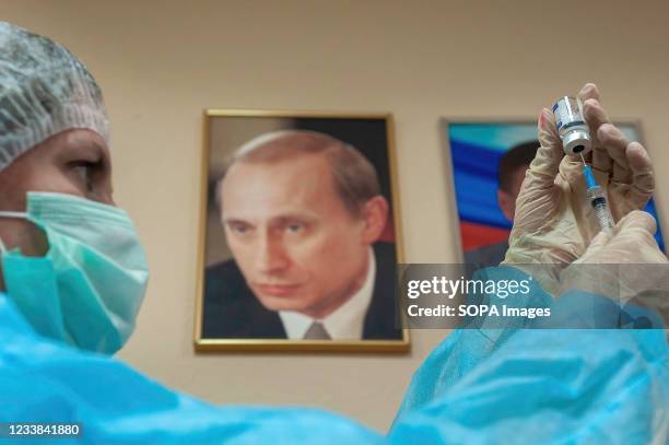 Nurse of the polyclinic No. 2 preparing the vaccine and a portrait of Russian President Vladimir Putin seen in the background. Employees of the...