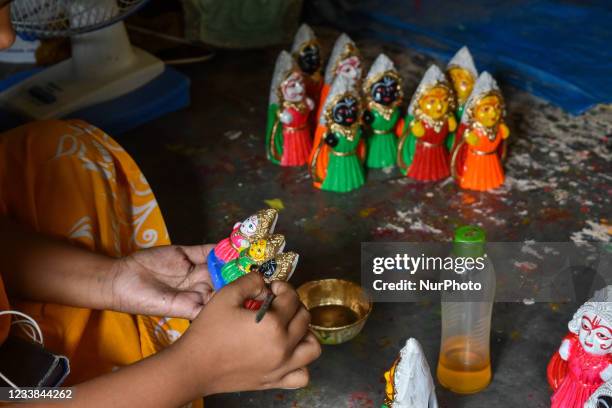 Girl giving final touches to an idol of Jagannath , Balram and Subhadra , at a potters hub , ahead of Rath -Yatra celebration in Kolkata , India , on...