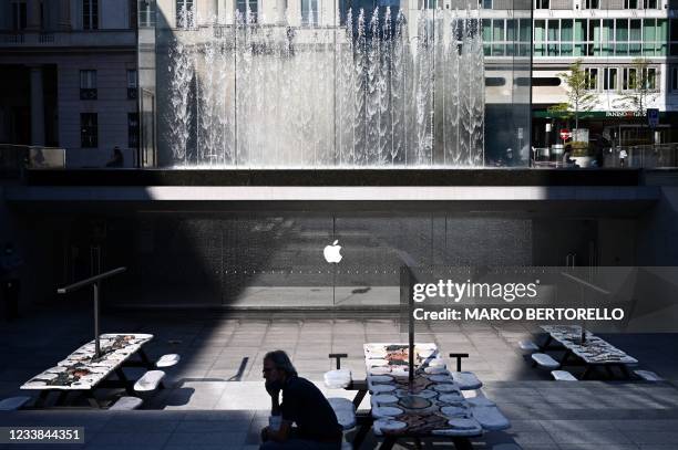 Man is silhouetted near the installation "The Moral of the Story", by French artist Neïl Beloufa, near the Apple Store in Piazza Liberty in Milan, on...