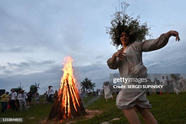 Girl wearing traditional Ukrainian clothes dances near a fire during the celebrations of the Kupala night in Pyrohiv, near Kiev, on July 6, 2021. -...