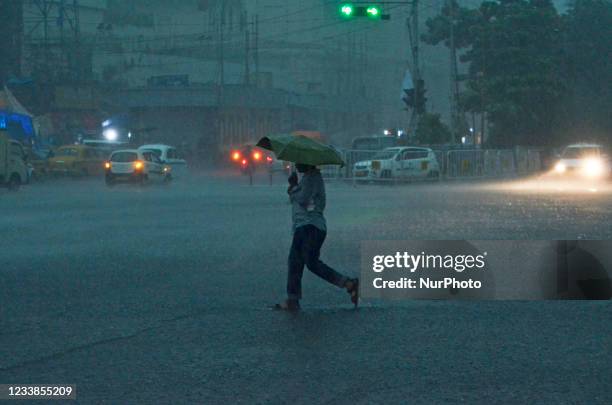 Man with an umbrella crosses a road during heavy rainfall in Kolkata, India, 07 July, 2021.